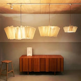 Three pleated fabric shades hung in a row above a sideboard