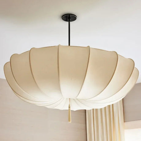 Ceiling light with a scalloped cream cloth shade against a pale curtain