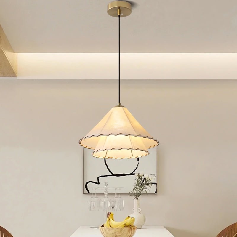 The two tier shade above a black round table with chairs and a dried plant vase