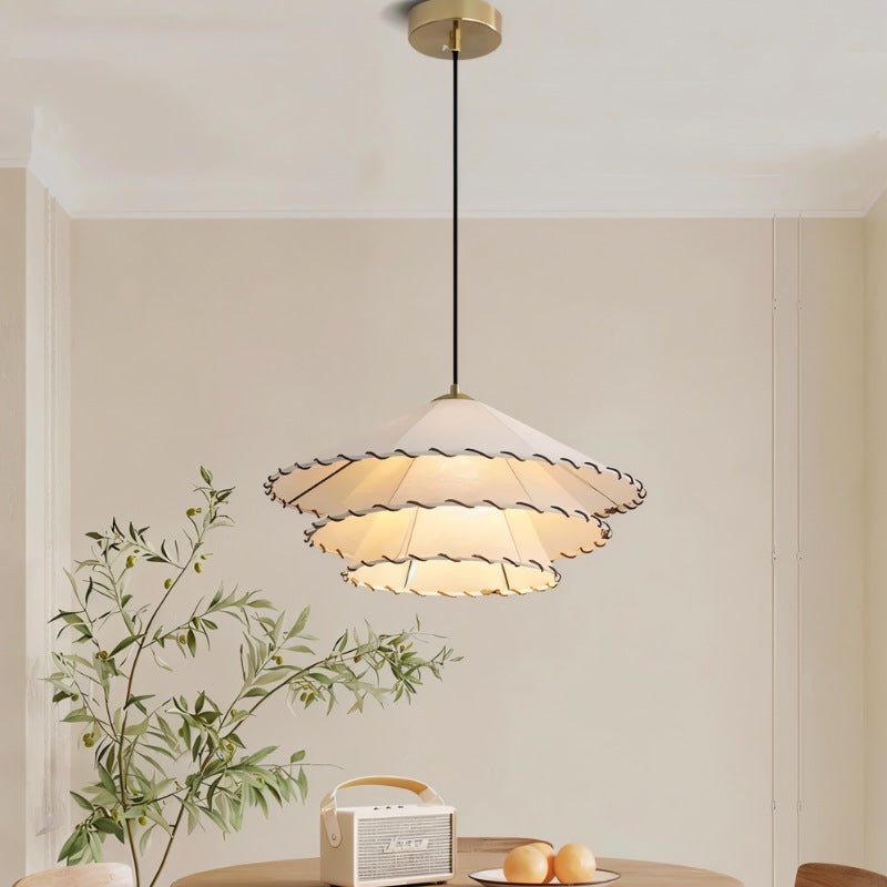 The two tier shade lit above a round table with a fruit bowl and cane chairs