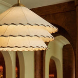 The stitched scalloped edges of three fabric tiers seen close under warm light