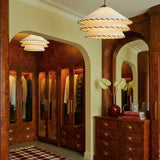 Two tiered shades lit in front of a burl wood wardrobe and an arched doorway