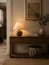 Ceramic bedside lamp lit on a sideboard seen through a doorway