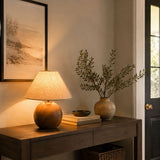 Ceramic bedside lamp lit on a console beside a vase of olive branches