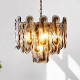 The amber glass petal chandelier lit against a pale wall