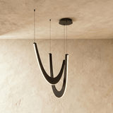Two nested black wood arcs hung on cables, each lit along its inner edge