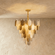 A round chandelier of tiered gold and white feather shaped glass shades, lit