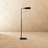 The same lamp in black, the flat head tipped forward above a small square base