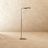 The same lamp in bronze, the flat head angled forward at the top of a slim stem