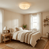Swirled glass ceiling light above a bed with linen covers and a wood nightstand
