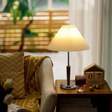 Chrome table lamp lit on a side table beside an armchair and a window