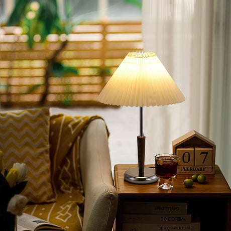 Chrome table lamp lit on a side table beside an armchair and a window
