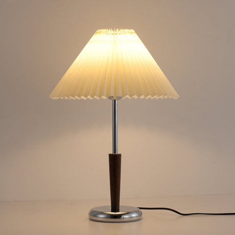 Chrome table lamp lit and seen from a short distance on a table