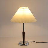 Chrome table lamp lit, the cord running away across the surface