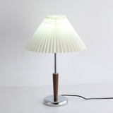Chrome table lamp switched on against a pale wall