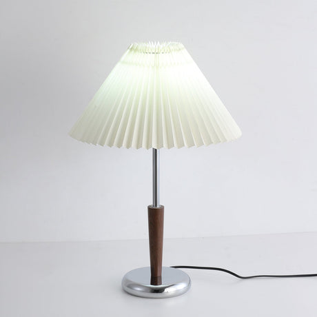 Chrome table lamp switched on against a pale wall