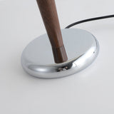Close view of the low oval chrome foot with the walnut stem rising from it