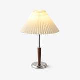 Chrome table lamp with a white pleated shade and a walnut stem, plain background
