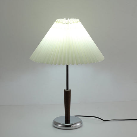 The pleated shade lit from inside above the chrome and walnut stem