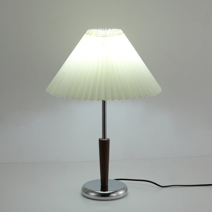 The pleated shade lit from inside above the chrome and walnut stem