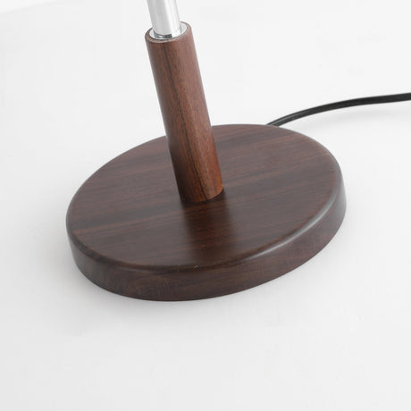 Close view of the round walnut disc base with the chrome stem rising