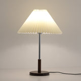 Chrome stem table lamp lit against a warm ground, the shade glowing amber