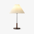 Chrome stem table lamp with a pleated cream shade on a walnut disc base