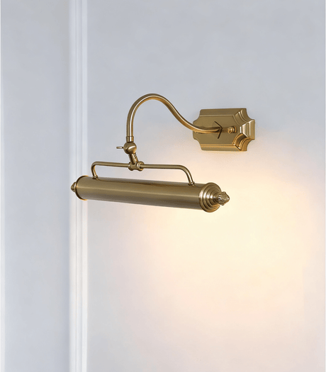 The gold version lit on a pale wall, the arched arm rising to the turned bar