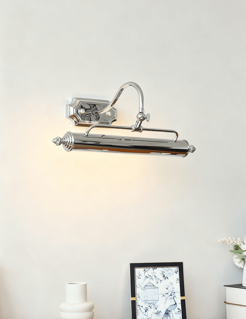 The chrome bar lit on a pale wall above a framed print and a ribbed vase