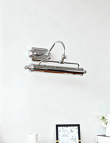 The chrome bar unlit on a pale wall above a small dark framed picture
