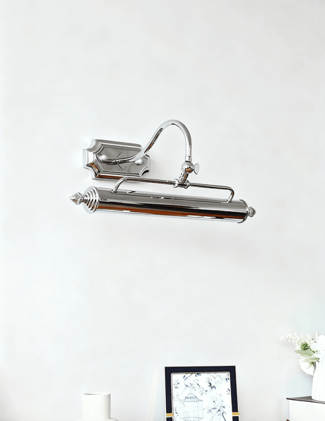 The chrome bar unlit on a pale wall above a small dark framed picture