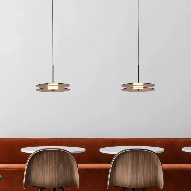 Two glass discs hung flat above a counter with curved chairs