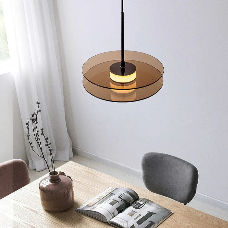 The amber glass disc hung flat above a desk with a chair behind it