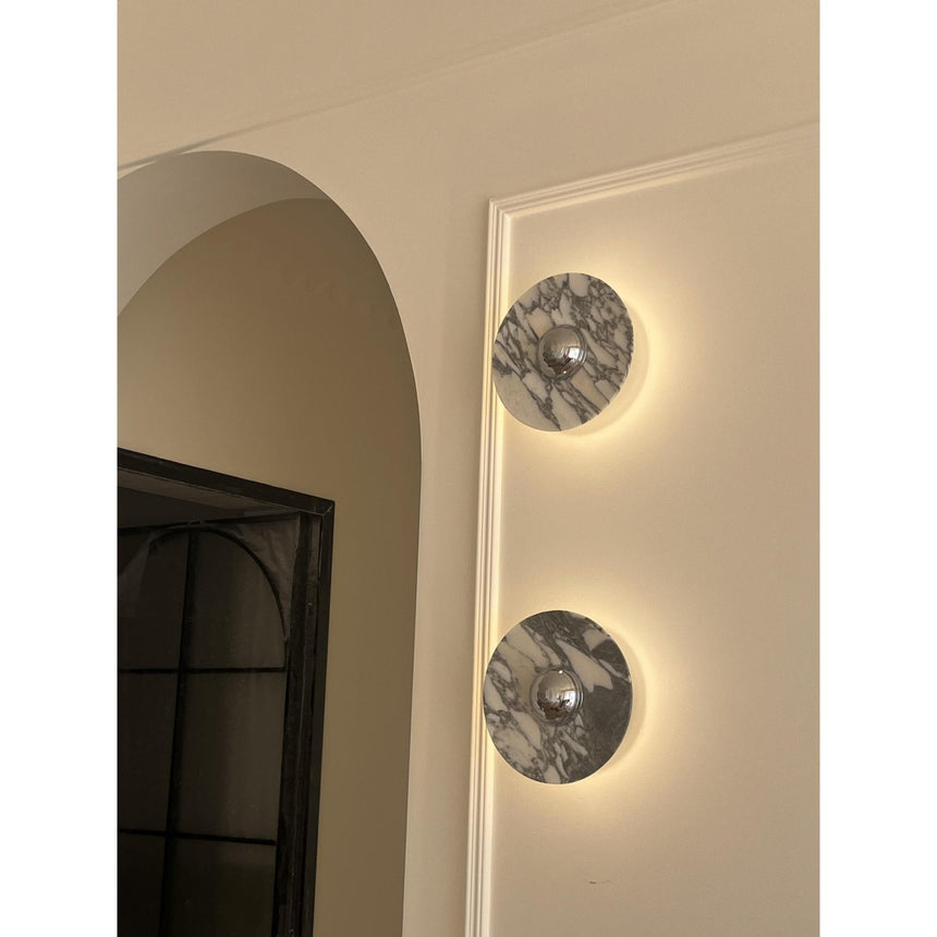 Two marble discs lit beside an arched doorway