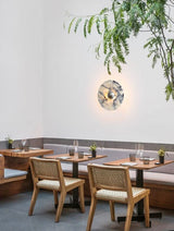 The marble disc lit above a dining table with cane chairs