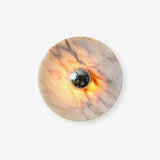 Round white marble disc wall light with a chrome center, glowing from behind