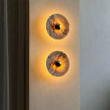 Two marble discs lit warm on a narrow wall beside a curtain