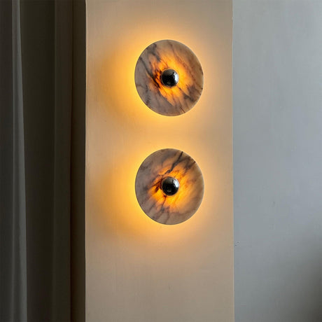 Two marble discs lit warm on a narrow wall beside a curtain