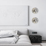 Two marble discs above a white sofa beside a large canvas
