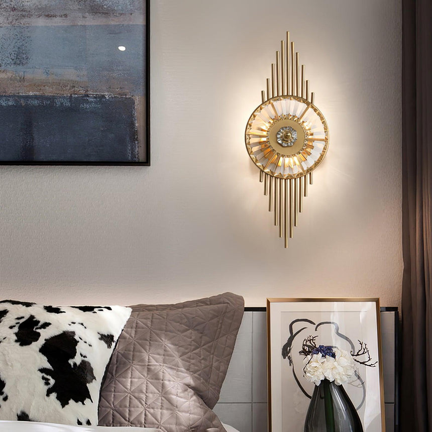The sconce lit above a bed with patterned pillows beside a framed painting
