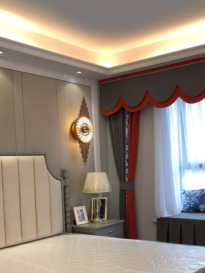 The sconce beside an upholstered headboard in a bedroom with red curtains