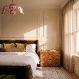 The red version lit above a bed with a burl wood dresser and a window
