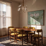 The clear version lit above a dining table with chairs, artwork and a rug