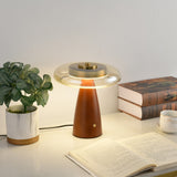 Clear glass table lamp lit beside a potted plant and books