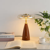 Clear glass table lamp on a cone base, lit beside white flowers
