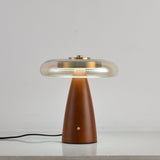 Clear glass table lamp on a cone base unlit against a pale ground
