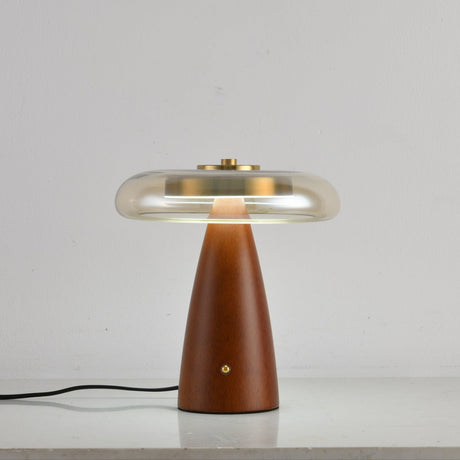 Clear glass table lamp on a cone base unlit against a pale ground