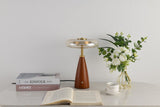 Clear glass table lamp on a cone base beside a vase of flowers
