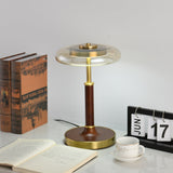 Glass disc lamp lit with a cooler light beside bound books