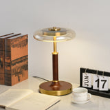 Glass disc lamp unlit on a desk beside an open book and a calendar